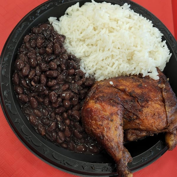 Mr. Jack's Peruvian Rotisserie Chicken with a side of white rice and black beans on a black plate.